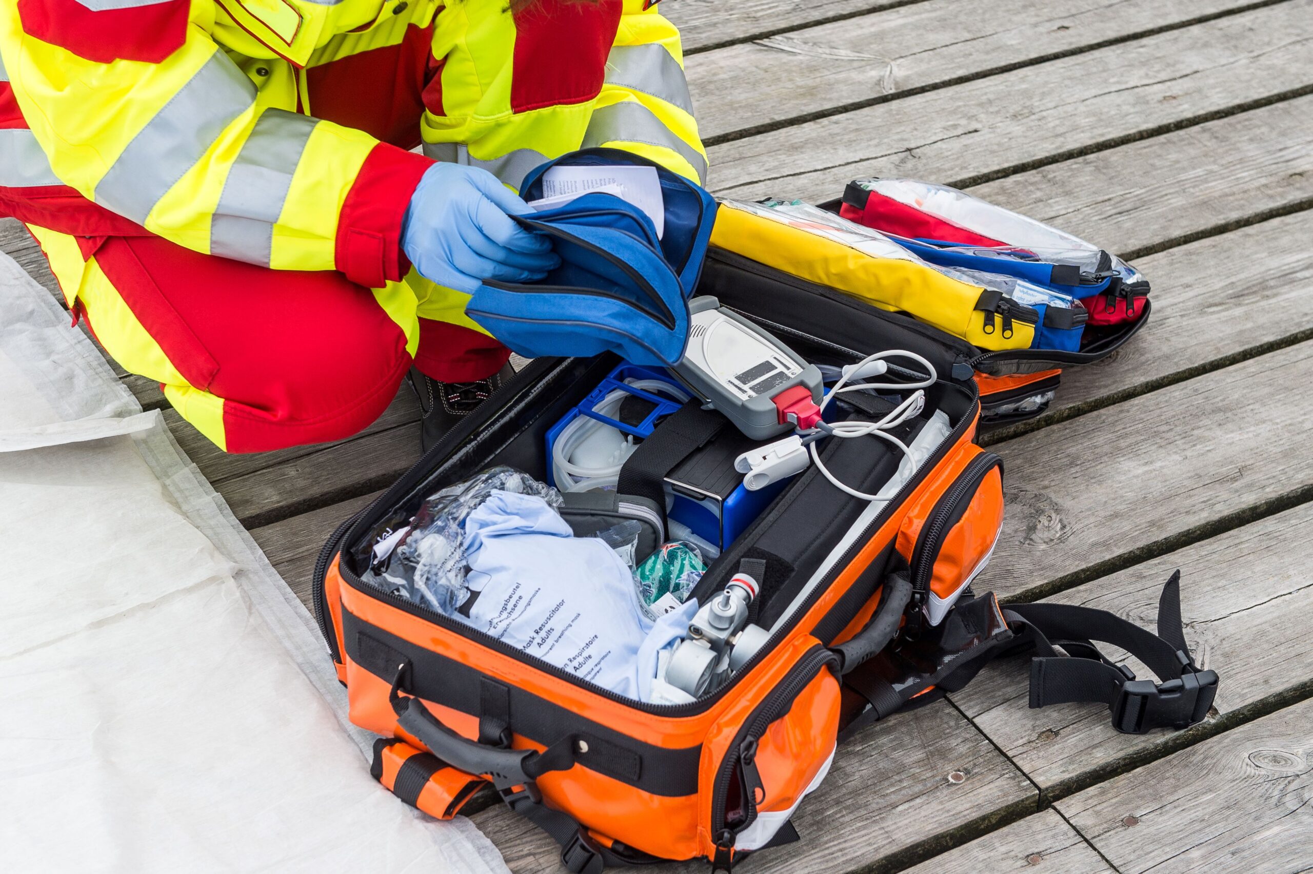 Sanitäter steht vor einem Koffer mit Erste Hilfe Gegenständen.